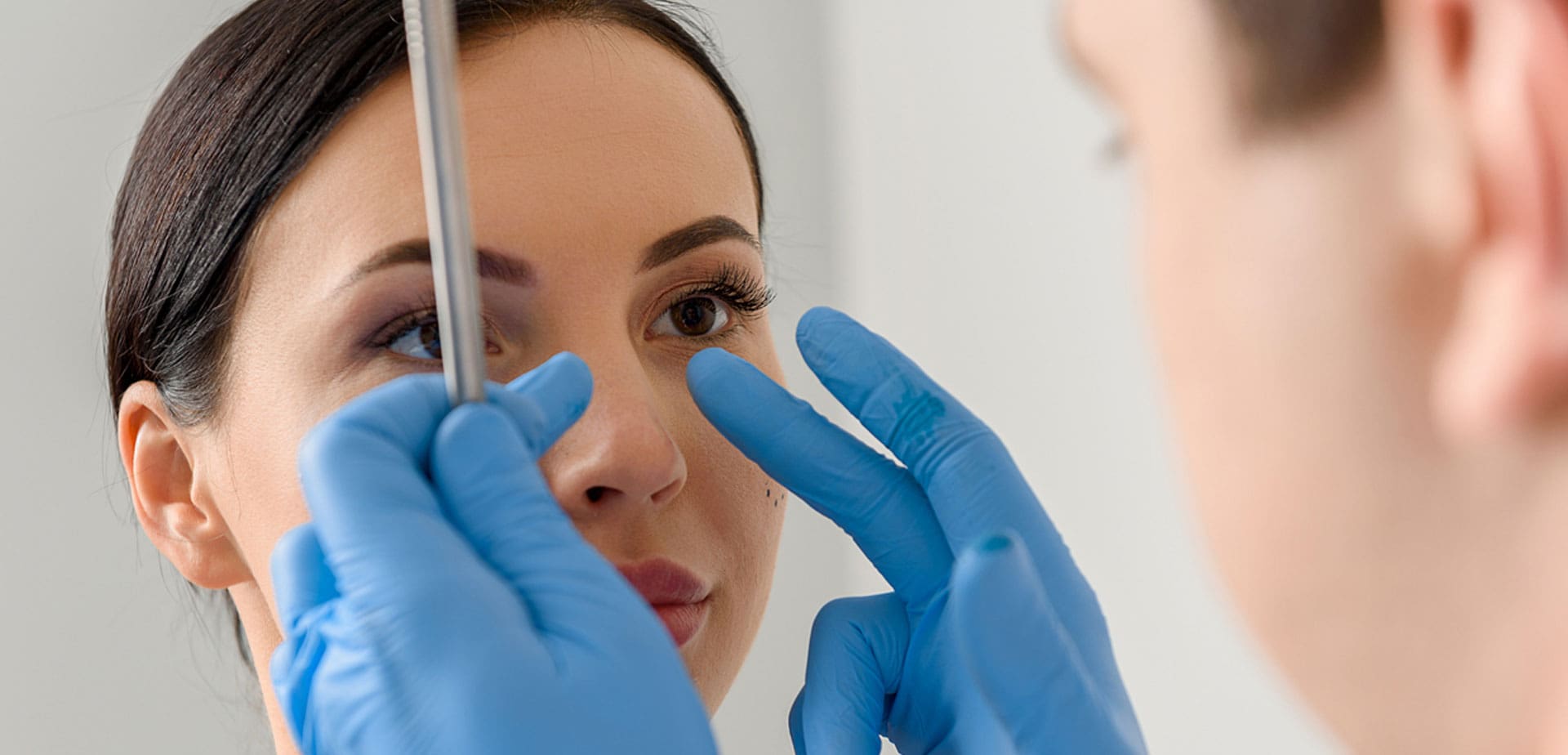 surgeon-in-gloves-marking-a-woman's-nose-before-a-procedure