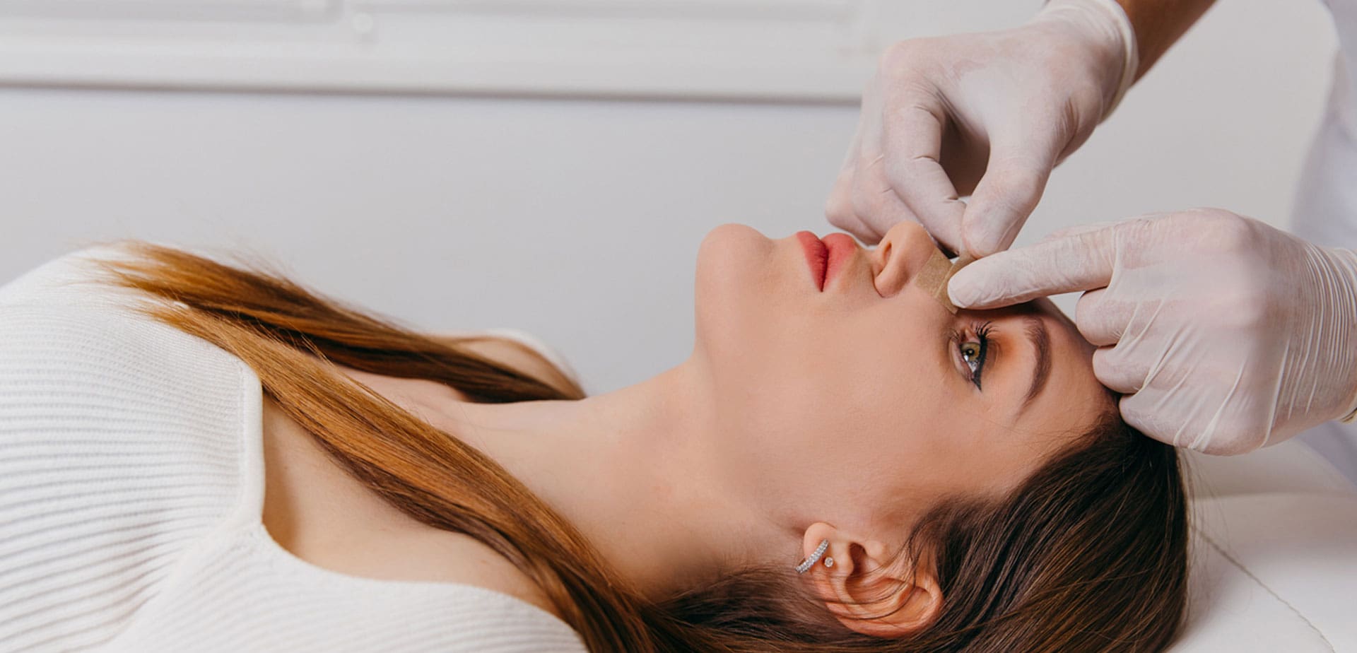 woman-lying-back-while-a-gloved-provider-examines-her-nose